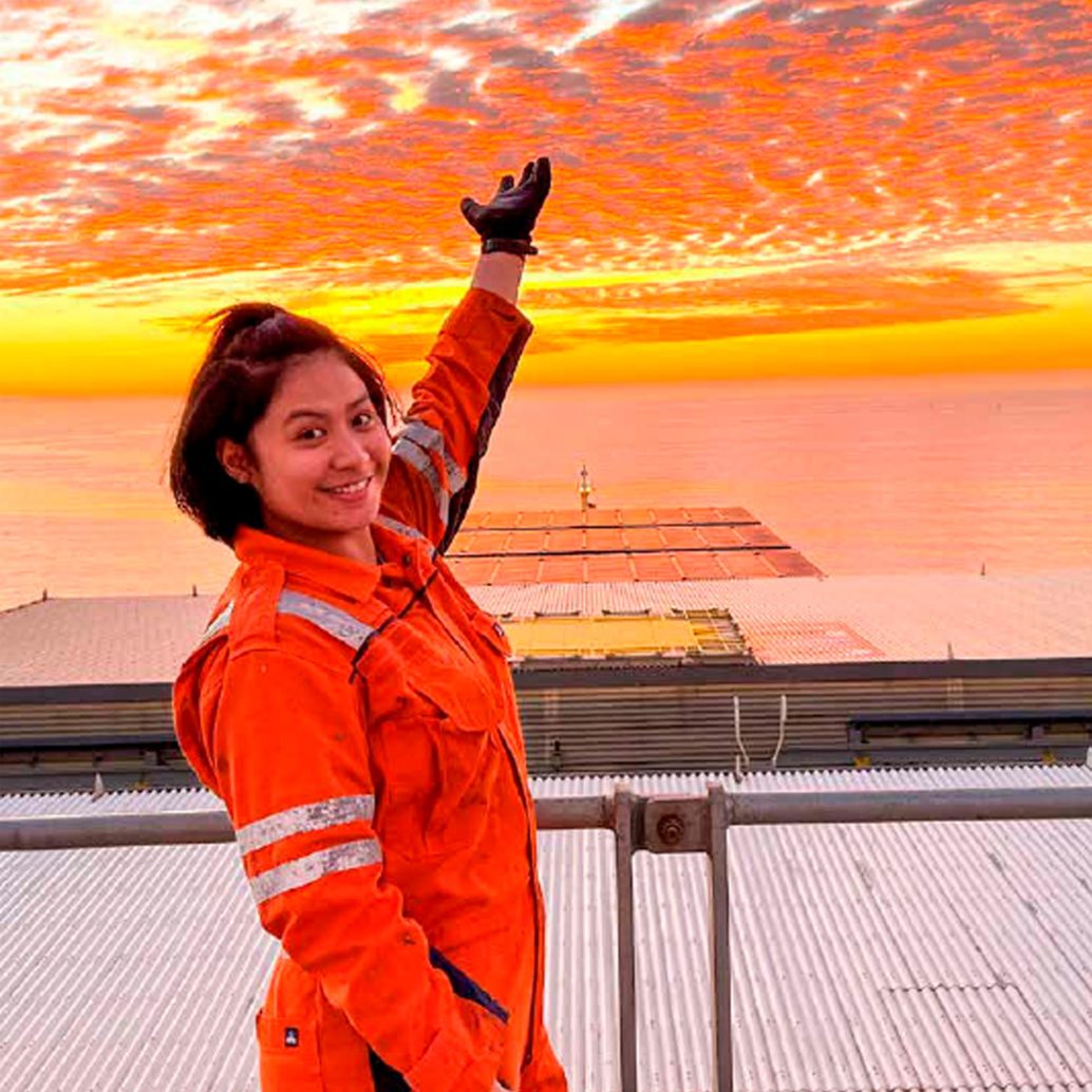 A female worker pointing up at the sky in sunset.