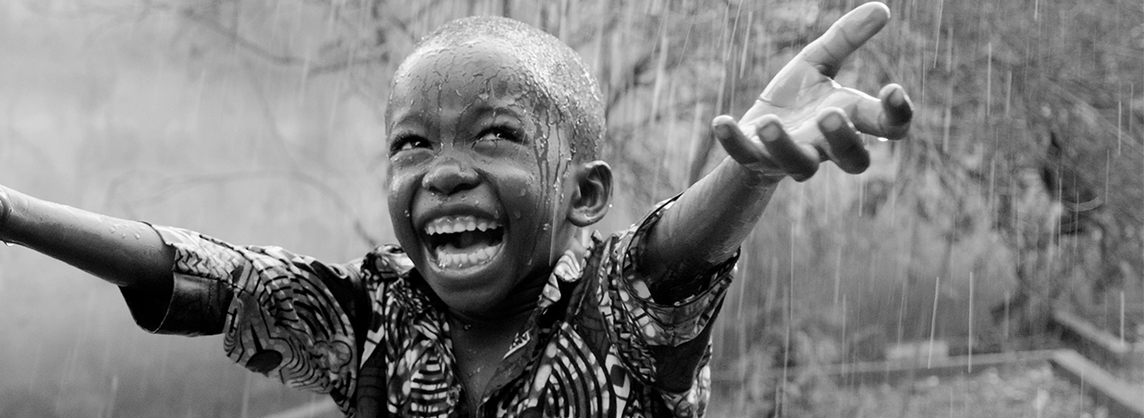 A happy african boy dancing in the rain.