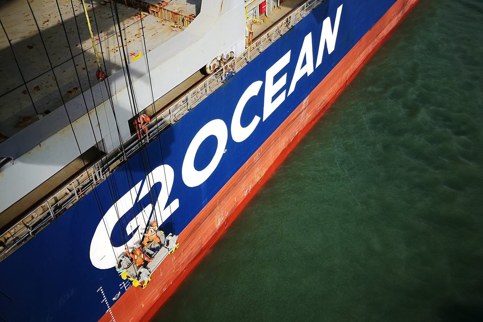 Two employees working on the side of a G2 Ocean vessel.