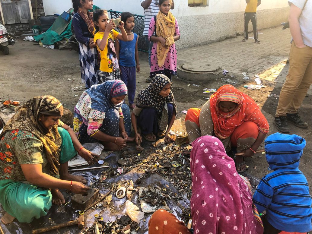 A group of Indian women sitting on the ground disassembling e-waste